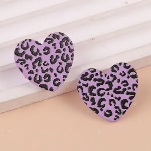 Primer plano de pendientes de acrílico con corazón estampado leopardo violeta, joya elegante.