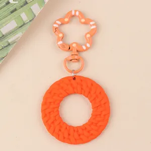 Porte-clés rond en acrylique orange texture tressée style bohème accessoire mode détail.