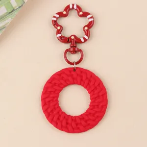 Gros plan sur le porte-clés anneau tressé fermoir fleur couleur bonbon rouge minimaliste