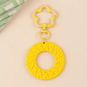 Gros plan détaillé du charmant pendentif de porte-clés rond tissé jaune vif avec fermoir fleur.