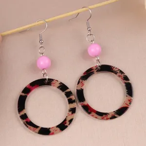 Close-up of retro leopard print acrylic circle earrings with pink beads and metal hooks.