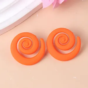 Close-up detail of vibrant orange geometric swirl acrylic stud earrings, stylish and bright.