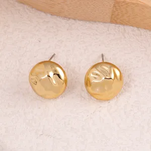Gros plan de boucles d'oreilles clous rondes texturées dorées, vue détaillée du design.