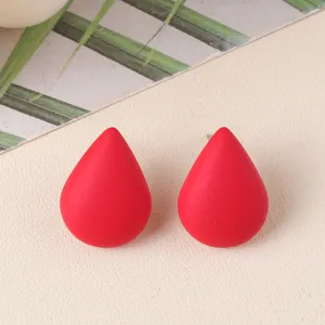 Close up view of vibrant red teardrop stud earrings, minimalist acrylic geometric jewelry