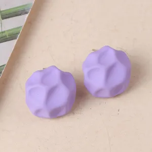 Primer plano de pendientes de tuerca de acrílico geométrico irregular morado con diseño minimalista.