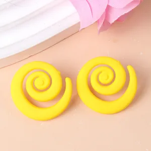 Close-up detail of bold yellow swirl acrylic stud earrings, unique candy color geometric style.