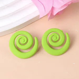 Close-up detail of bold green spiral acrylic stud earrings, geometric candy-colored statement jewelry.