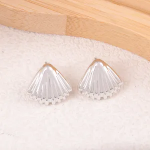 Gros plan de boucles d'oreilles clous coquillage argentées avec un beau design texturé.