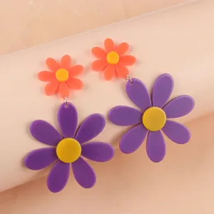 Gros-plan détaillé de boucles d'oreilles pendantes tournesol en acrylique violet et orange.