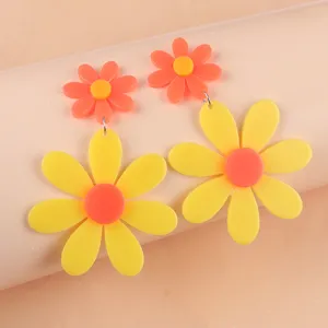 Gros plan détail des boucles d'oreilles tournesol en acrylique néon vif multicouche.