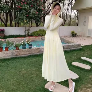 Outdoor scene detail of a lightweight long hooded yellow sun protection dress in garden.