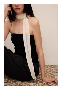 Detailed view of an elegant white pleated narrow scarf worn by an Asian model in a stylish look.