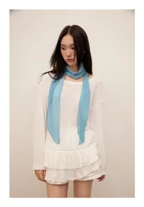 Detail view of light blue pleated narrow scarf worn by model for elegant spring neck decoration.