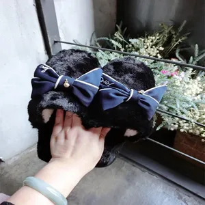 Close-up of handmade women's plush slippers with elegant navy bow and soft faux wool lining.