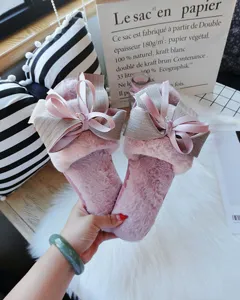 Details of fluffy pink slippers for women with elegant handmade bow, cozy indoor winter wear.