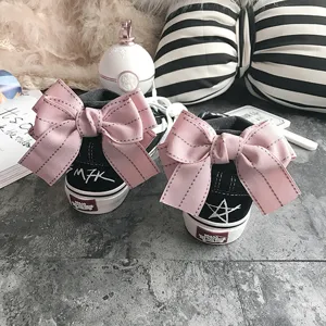 Black high top canvas shoes featuring sweet pink bow decor at the back, stylish street look.