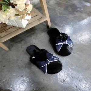 Black fluffy faux wool slippers for women featuring a large navy blue bow detail and cozy design.