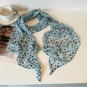 Close-up detail of light blue long silk scarf with brown polka dots, soft fabric texture.