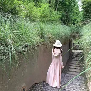Detailed outdoor view of a women's long pink hooded sun protection coat with stylish draped design.