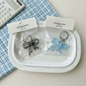Clear acrylic bow keychain detail shot, featuring transparent printed bows for bags.