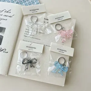Detailed view of clear acrylic double-sided printed bow keychain charm for stylish bags.
