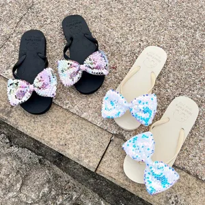 Detail shot of women summer beach flip-flops featuring large sparkling sequin bows and comfortable design.