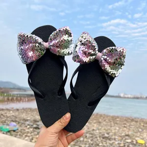 Detail shot of women beach flip-flops featuring large sparkly sequin bows and comfortable black sole.
