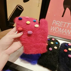Close-up view of cute rabbit hair mittens with colorful pom-poms for winter warmth style.