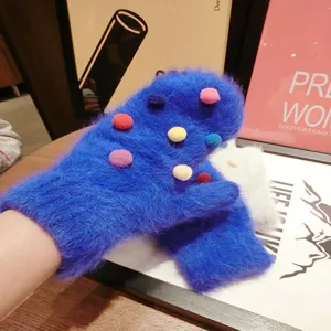 Detailed view of fluffy winter blue mittens featuring cute colorful pom pom cozy style.