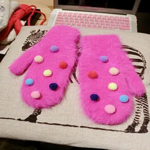 Cute pink rabbit hair mittens with colorful pom-poms, cozy winter warm fashion accessories.