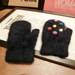 Close-up of cute fuzzy rabbit hair mittens with colorful balls, cozy winter accessory.