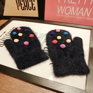 Cute fluffy rabbit fur mittens with colorful pom-poms, warm winter gloves detail view.