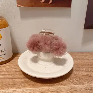 Gros plan détaillé de la pince à cheveux en fourrure de vison rose douce et duveteuse.