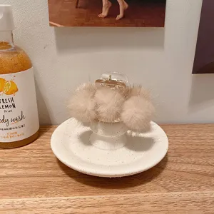 Vue rapprochée détaillée de la pince à cheveux en vison duveteux beige, accessoire élégant.