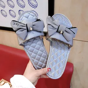 Détail de pantoufles en satin gris avec nœud mignon et pendentif en métal pour le printemps.