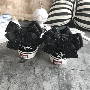 Detailed view of cute black canvas shoes featuring large back bow knots and embroidered heels.