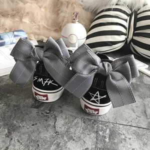 Black canvas low-top sneakers featuring large grey bow knots and creative back heel graffiti prints.