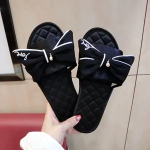 Vue détaillée de pantoufles plates pour femmes en satin noir avec un grand nœud élégant.