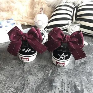 Detailed shot of black canvas shoes with large maroon bowknot and heel embroidery designs.