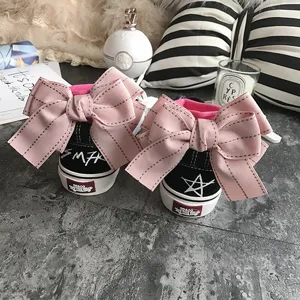 Black canvas sneakers featuring large pink bows on the back and unique heel patches for women.