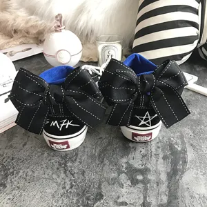 Black high-top canvas sneakers featuring large back bows and unique handwritten graffiti details.