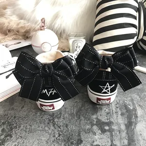 Black canvas sneakers featuring oversized decorative bows and embroidered details on heel.