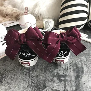 Black canvas sneakers featuring large maroon ribbon bows on back and cool graffiti star prints.