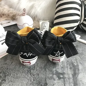 Detailed view of trendy black canvas sneakers featuring oversized back bow and yellow inner lining.