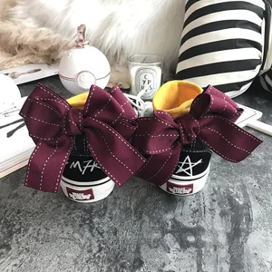 Black high-top canvas sneakers with large maroon bow, stylish casual shoes for women.