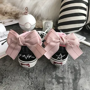 Black canvas sneakers with pink oversized bow socks, sweet and cute fashion detail view.