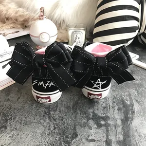 Black canvas sneakers featuring oversized decorative bows on the heel and stylish contrast lining.