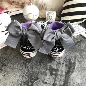 Black canvas sneakers featuring oversized grey bows at the heel and unique graffiti details for women.
