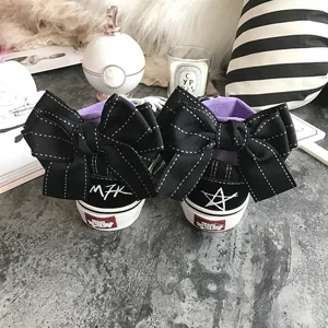Black canvas low top sneakers featuring oversized bow decor and cute street style design.