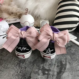 Black canvas sneakers featuring oversized pink bow decor, purple lining, and unique heel design.